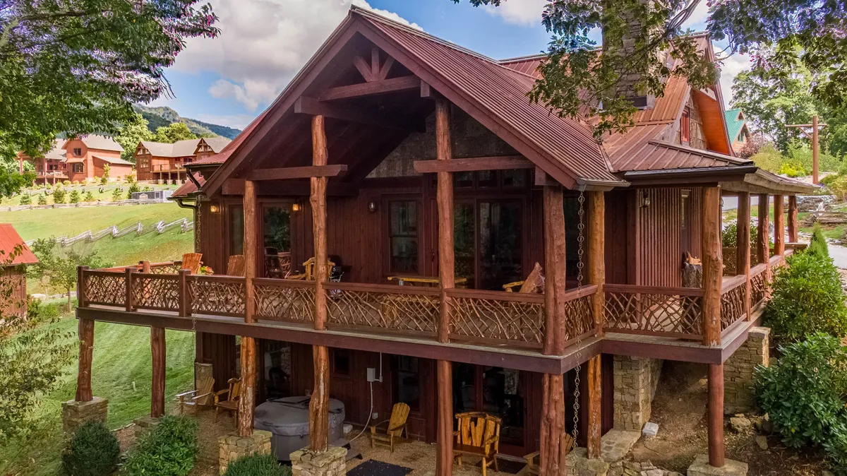 A welcoming exterior view of the property’s wooden porch and sturdy stone foundation set against a beautiful mountain landscape. The space invites guests to enjoy nature walks, gatherings, or simply soak in the peaceful surroundings.