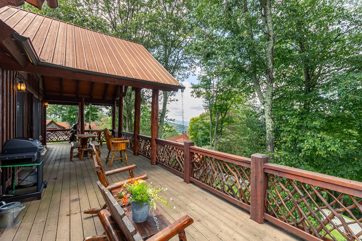 This image showcases a spacious wooden deck furnished with outdoor seating and a grill, surrounded by lush greenery and decorative plants. The deck appears inviting for gatherings, barbecues, and moments of relaxation, with natural views enhancing the ambiance.
